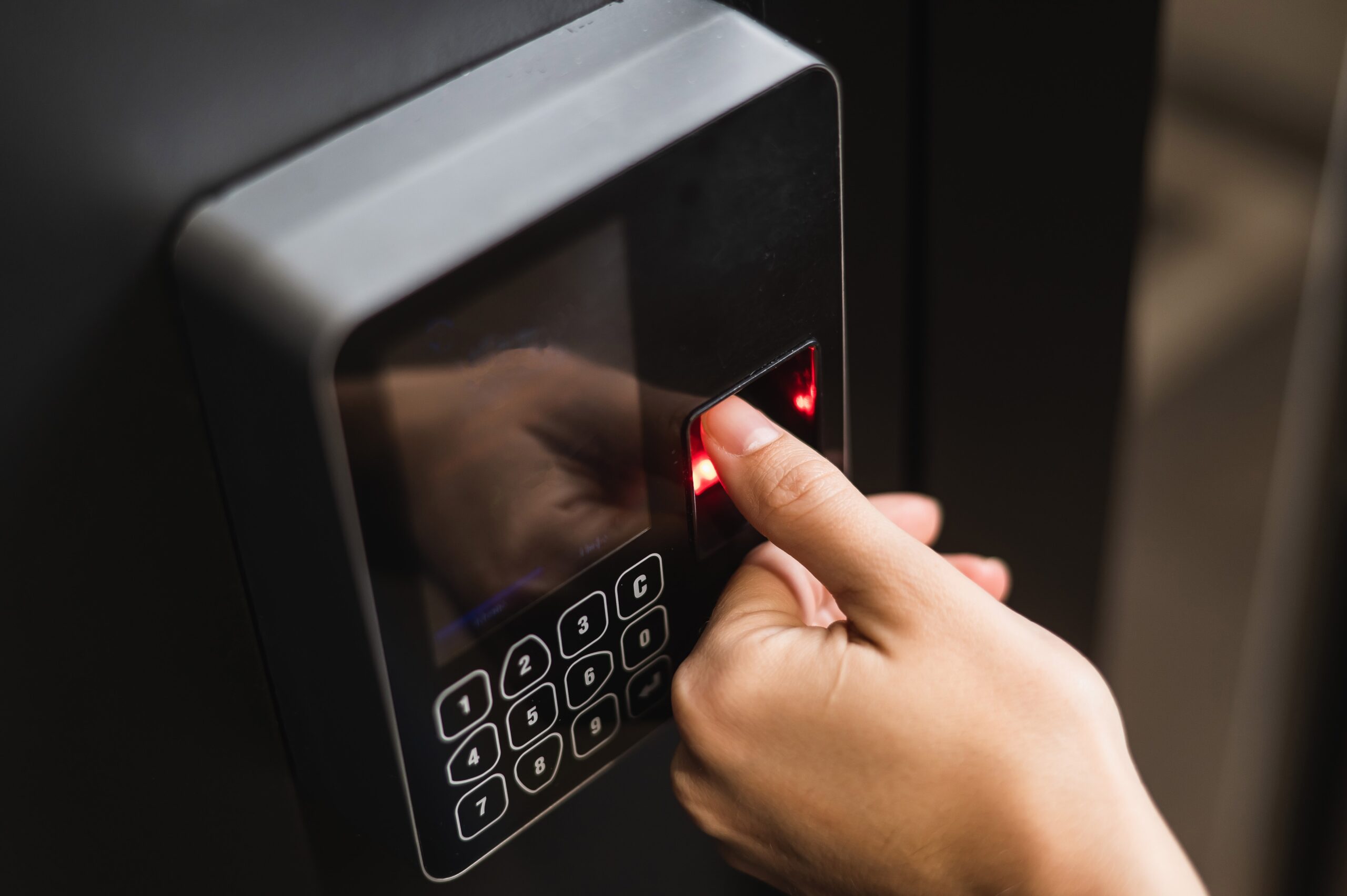A,Woman,Opens,The,Door,With,Her,Fingerprint.,Modern,Keyless A person places their finger on a fingerprint scanner of an electronic device with a numeric keypad.